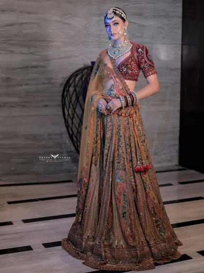 A full-length portrait of the bride in a unique, heavily embroidered lehenga, showcasing a modern royal look.