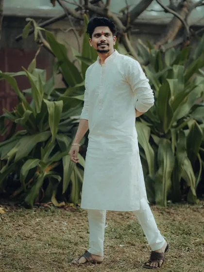 A handsome portrait of the groom-to-be, Abhishek, in a classic white kurta. This shot captures a moment of quiet confidence before the wedding.
