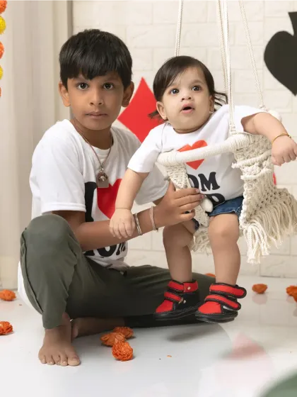 Two siblings pose for a Raja Parba festival shoot, with the younger one on a traditional swing, celebrating our local culture.
