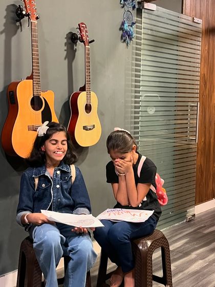 Two young students sharing a laugh during a class. Our goal is to make learning music a joyful and memorable experience.