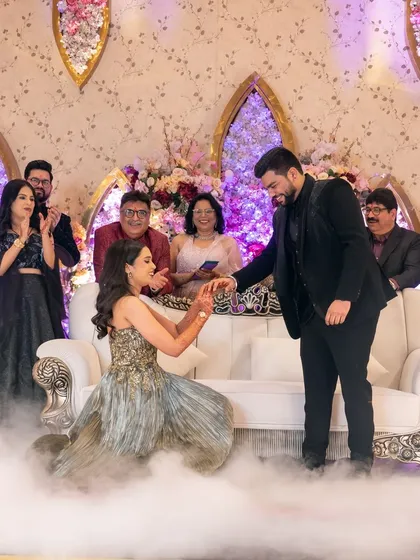 A unique twist where the bride proposes to the groom, a beautiful moment of modern love captured amidst family cheers.
