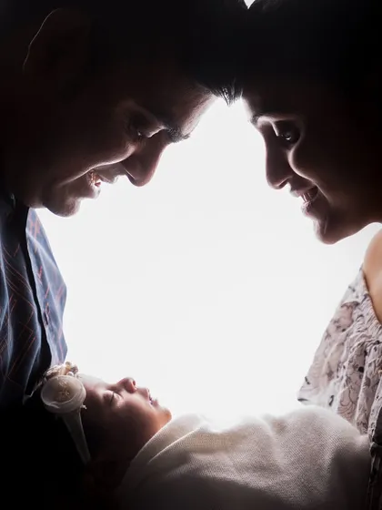 In this silhouette, the parents' profiles create a heart shape around their newborn. It’s a creative composition that visually represents the love that surrounds the new baby.