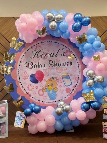 A close-up of the baby shower setup, showing the custom printed backdrop and the butterfly accents on the balloon arch.