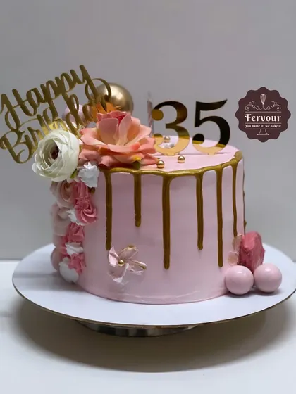 A simple and pretty drip cake for a 35th birthday. This pink chocolate truffle cake is decorated with a gold drip, flowers, and a custom topper.