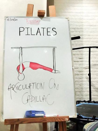 A whiteboard sketch illustrating spinal articulation on the Cadillac, a key concept for many advanced exercises on this apparatus.