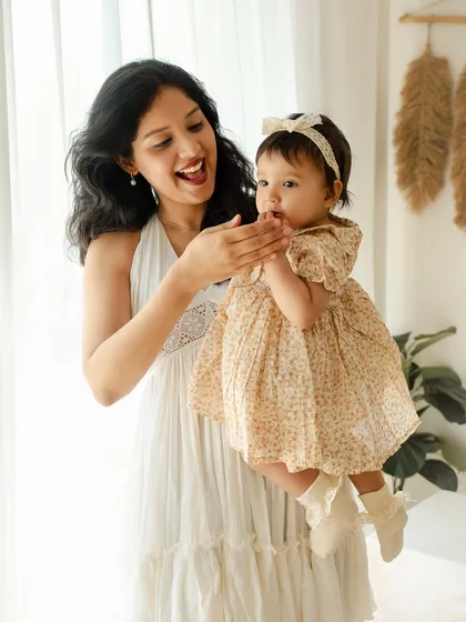 A mother's delight in her one-year-old daughter. Her expression of pure joy and the baby's curious gaze create a lively and heartwarming portrait.