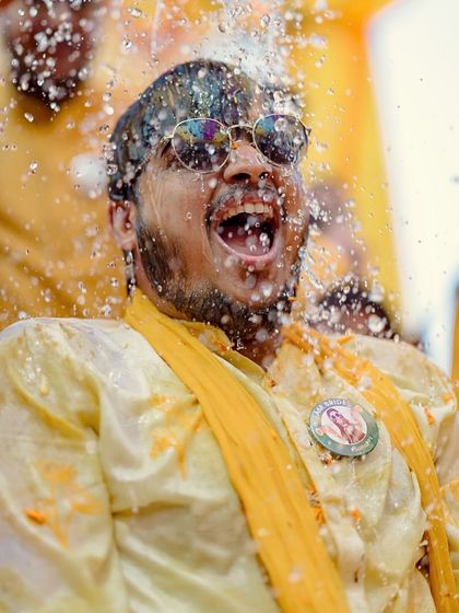 The groom's turn for a water splash! His reaction is a perfect capture of the fun and games of a Haldi ceremony.