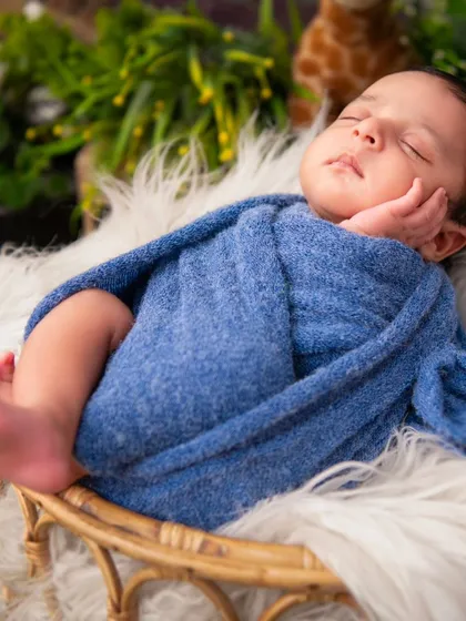 A slightly different angle of a newborn sleeping in a wicker basket, swaddled in blue. This shows how we capture multiple perspectives during a session to provide a variety of beautiful shots.