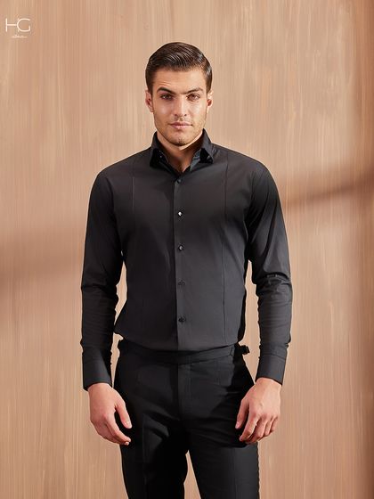 A straight-on view of the all-black shirt and trouser look. It's a powerful, sleek, and timeless ensemble for the modern man.