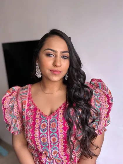 A fresh and pretty look for a daytime event. The client's pink printed outfit is paired with soft pink makeup and loose, flowing waves.