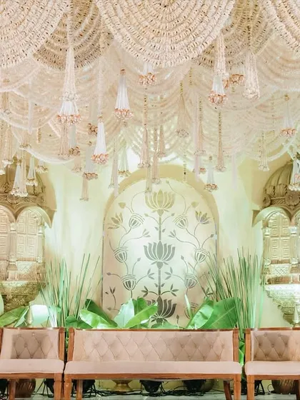 The full stage setup for the 'Whispering Willows' theme, with elegant seating arranged before the ornate jharokha backdrop. The design is balanced, grand, and steeped in cultural richness.