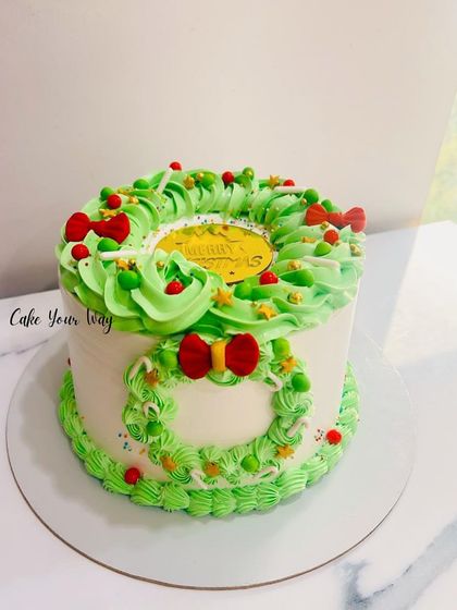 A Christmas wreath cake with festive green piping and red bows.