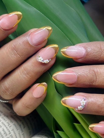 A glamorous fusion of a deep cat eye base with a golden chrome French tip. This set is all about luxury, combining a magnetic shimmer with a metallic finish and delicate floral accents.