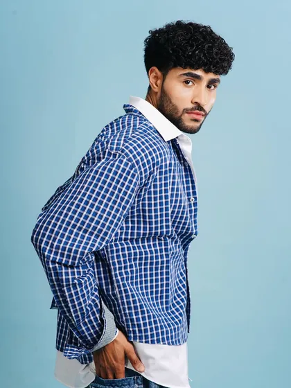 A casual and cool studio look. The grooming is natural, with a focus on defining the curls and keeping the skin looking fresh and clean.