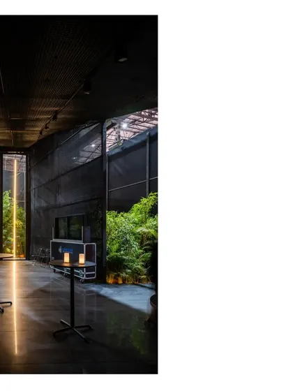 The dark, moody interior of the Durall Pavilion, with simple tables and candles. The space was designed to be a respite, a place for quiet conversation and introspection.