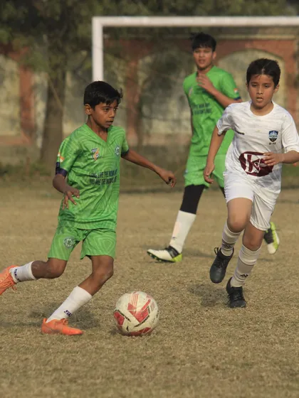 A young player driving the ball forward during a competitive match. We encourage creativity and confidence from our grassroots teams all the way up.