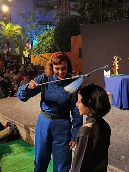 A performer from 'Volar Volar' interacts with a young audience member, using a prop from the show to create a fun and personal moment.