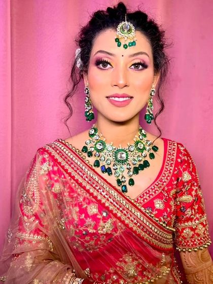 Another angle of the bride in the red lehenga, showing how the green Kundan jewellery beautifully contrasts with the outfit.