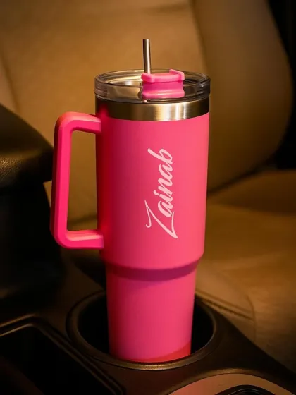 My personalized tumblers are perfect for anyone on the go. This hot pink travel mug is engraved with a name in a stylish script and comes with a handle and straw, making it both practical and chic.