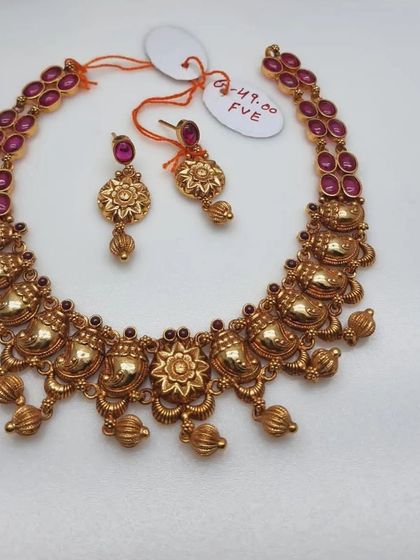 This simple yet elegant temple necklace set is made from 92.5 silver with gold plating. It features ruby-colored stones and comes with matching earrings.