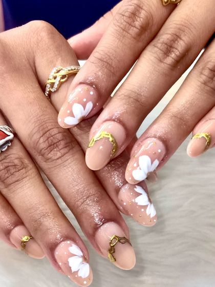 Another angle of the elegant floral and gold nail set, showing how the light catches the subtle gold shimmer and highlights the hand-painted white flowers.