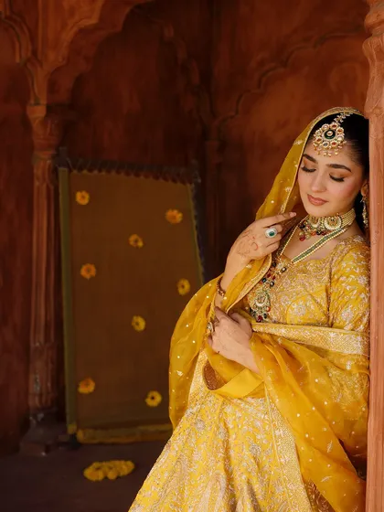 A dreamy, artistic shot. The soft lighting highlights the glowing makeup and the intricate details of the jewellery.