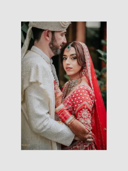 An intimate and romantic portrait. The couple is captured in a close embrace, with the bride looking directly at the camera, creating a powerful and engaging image.
