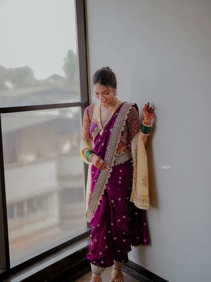 A full view of the bride's purple Nauvari saree and her complete look. The elegant draping and hairstyle come together for a timeless wedding day appearance.