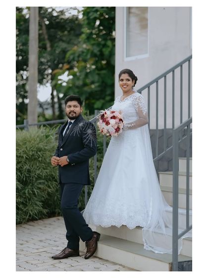 A stylish portrait of the couple. The groom's detailed suit and the bride's elegant gown are captured in a formal yet relaxed pose.
