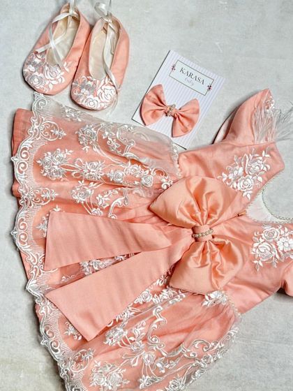 Another view of the peach lace dress set, showing the delicate feather details on the shoulders and the large bow at the back.