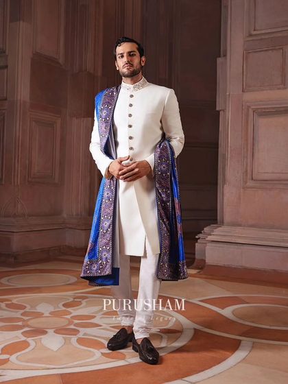 An ivory bandhgala paired with a vibrant blue and purple patterned shawl. I love using a striking accessory like this to add a personal and unexpected touch of color to a classic ensemble.