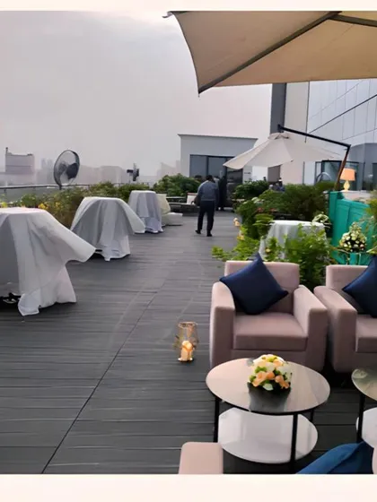 A daytime view of the rooftop event space being prepared, with lounge furniture and umbrellas positioned to provide comfort for guests.