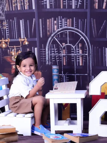 This happy two-year-old is sitting at a desk in our vintage library setting, smiling for his birthday portrait.