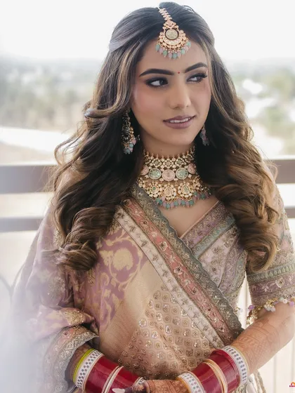 A stunning pastel bridal look with soft waves and a maang tikka, perfect for a modern bride.