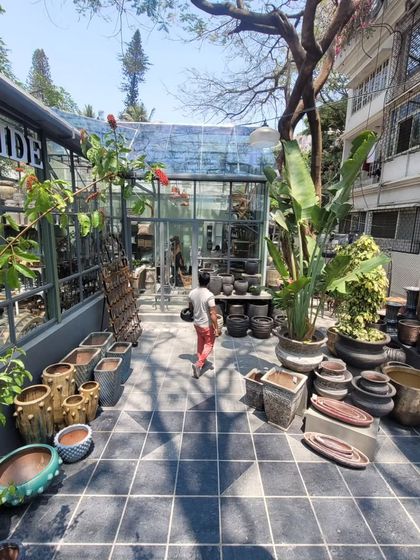 The layout of the store encourages wandering and discovery. Here, a path of black and white checkered tiles leads towards a glasshouse structure, with an array of pots and planters displayed like treasures.