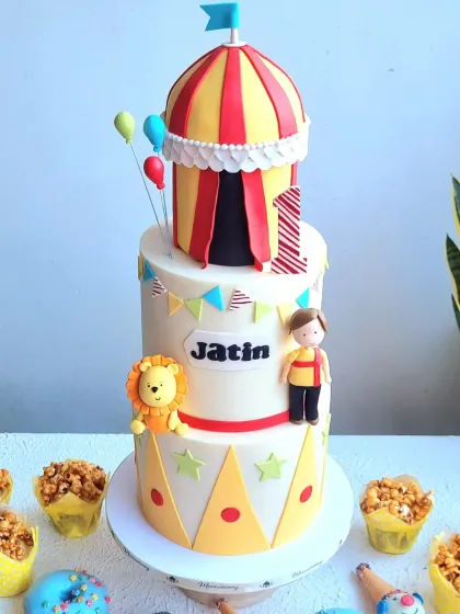 A three-tiered carnival cake with a big top tent, fondant figurines, and matching treats. This project is great for learning how to build tall cakes and create a variety of fun, themed elements.