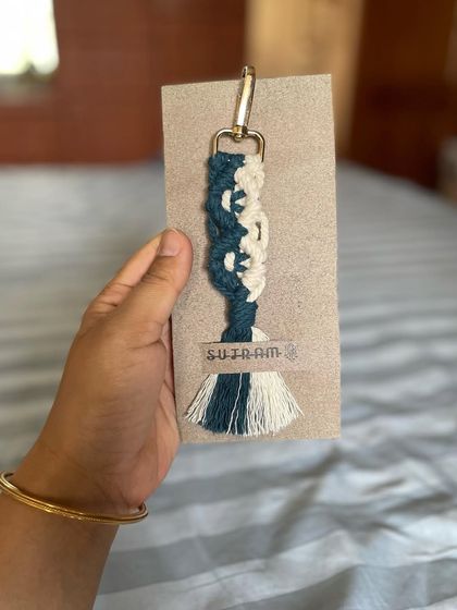 Holding up a packaged dual-toned keychain. The simple cardboard backing is perfect for gifting.