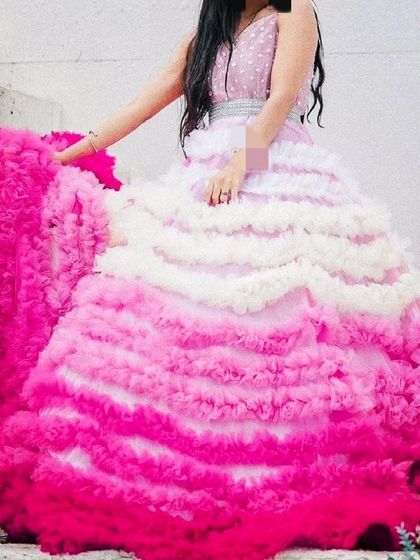 This unique ombre ruffled gown is a true work of art. The colors transition from white to shades of pink, creating a stunning visual effect that is perfect for a high-fashion photoshoot.