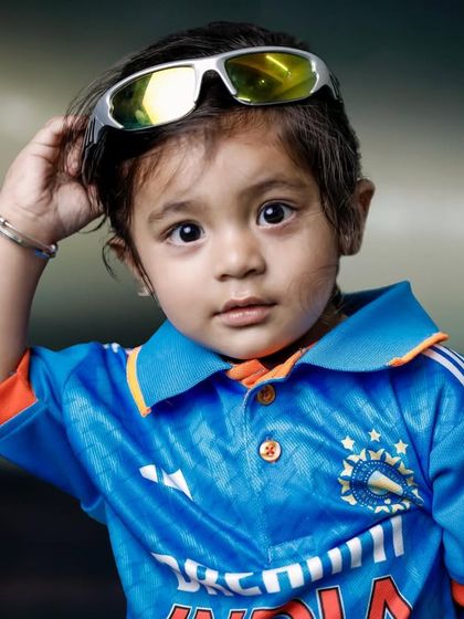 This little guy is looking cool and confident in his Team India jersey and sunglasses. It's a portrait full of style and personality.