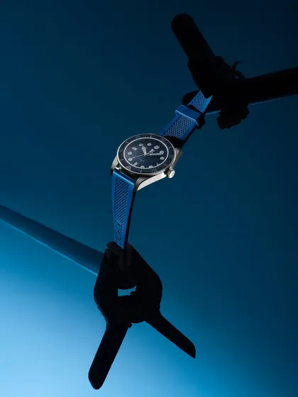 A behind-the-scenes glimpse of how a product shot is made. Here, a luxury watch is held in place with a clamp for a perfectly stable and clean shot against a blue background.