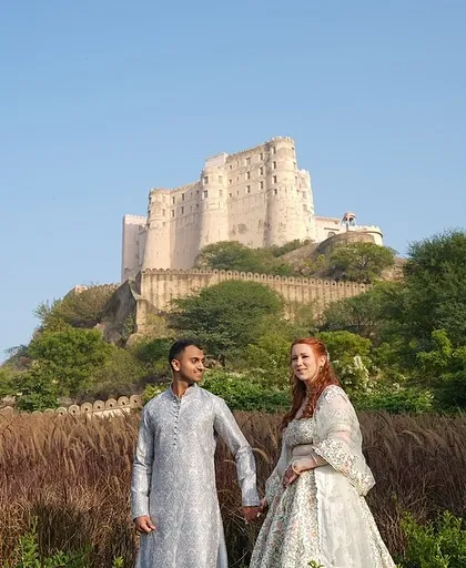 A wide shot of the couple in front of Alila Fort, capturing the scale and majesty of their chosen wedding destination.