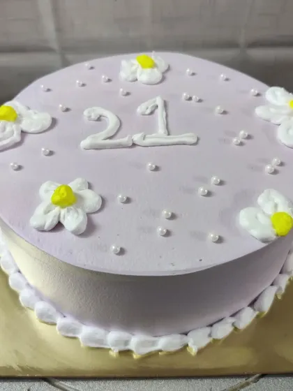 A simple and sweet 21st birthday cake. The light purple frosting is decorated with small white flowers.