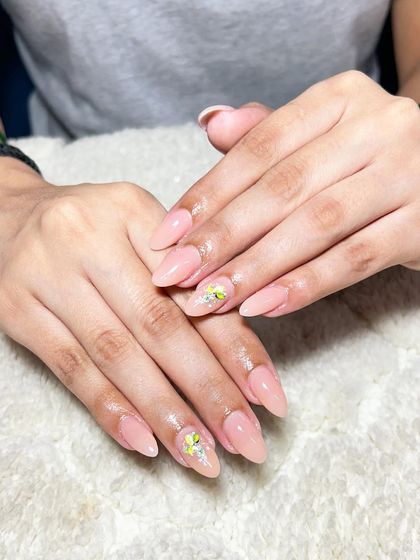 A subtle and sweet design. These natural-looking almond extensions have a sheer nude base with delicate yellow flower art.