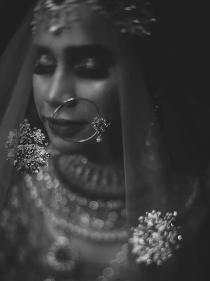 A moody and artistic black and white portrait of the bride. The use of a soft focus and veil creates a mysterious and beautiful image, highlighting her traditional jewelry.