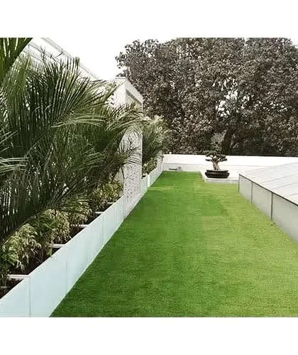A long shot of a terrace garden, showing how we can use planters and a strip of lawn to green the edges of a rooftop, preserving the open space while adding a natural touch.