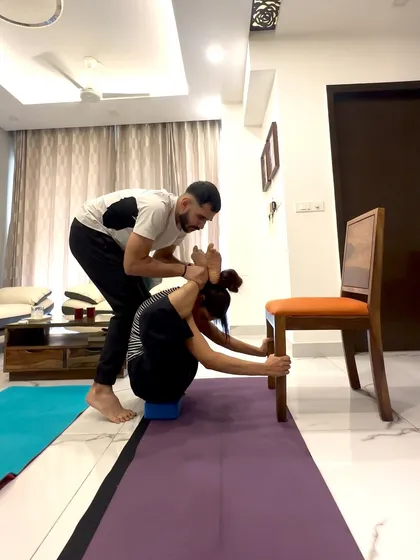 A closer look at the Dwi Pada Sirsasana assistance. My hands guide her feet and support her back, helping her understand the mechanics of this deep forward fold.