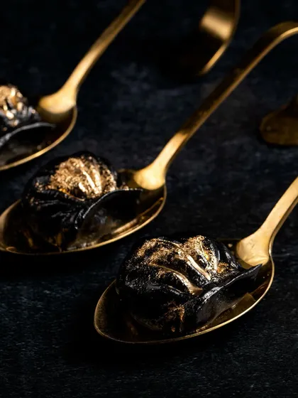 An appetizer that makes an impression. These prawn dimsums are wrapped in activated charcoal wanton sheets, filled with ginger and water chestnuts, and finished with gold dust.