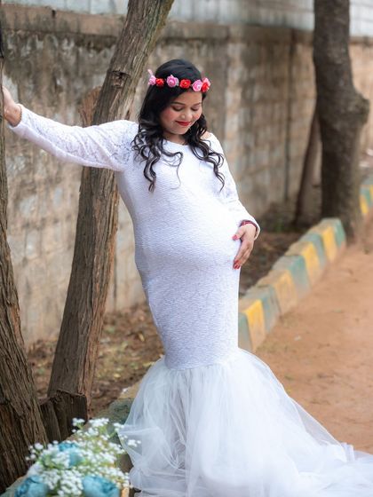 A beautiful outdoor portrait of a mom-to-be in a white lace gown and floral crown.