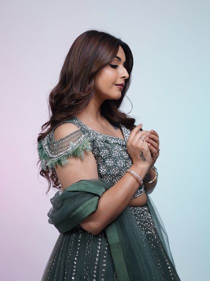 A close-up of the dark green lehenga, focusing on the delicate feather and sequin details on the shoulder. It's all about the craftsmanship.