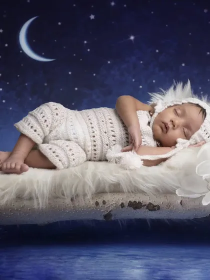 A peaceful scene of a baby sleeping on a rustic bed under a starry night sky with a crescent moon.